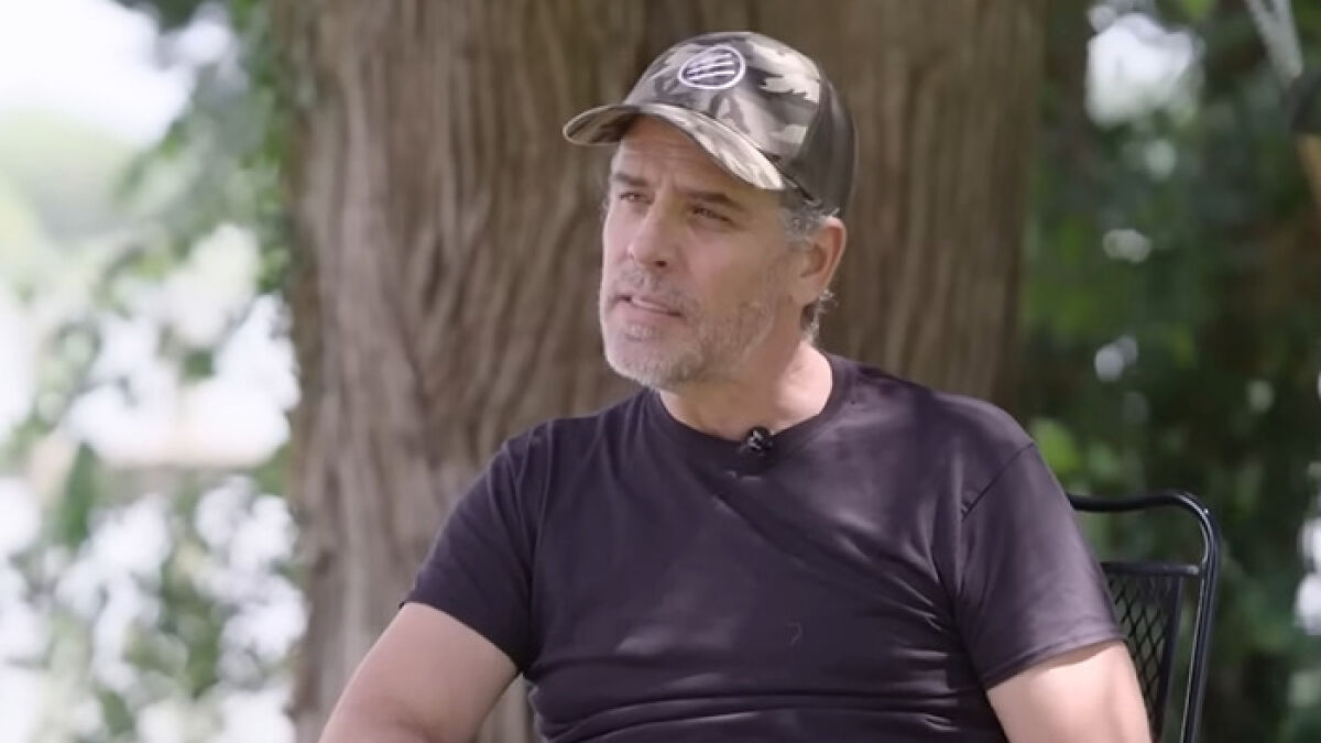 Man in a black shirt and camo hat sitting outdoors near a tree, related to Prince Andrew book and Jeffrey Epstein claims.