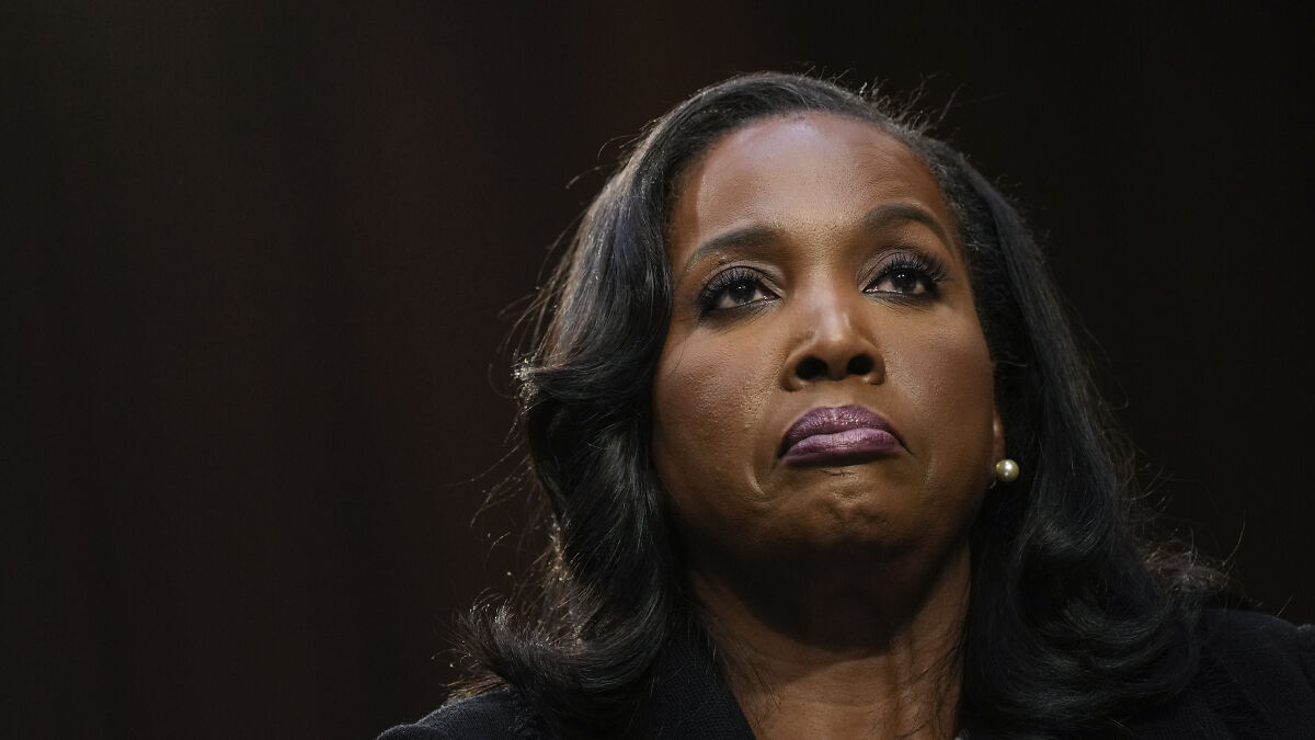Lisa Cook, the Fedu2019s first Black woman governor, with a determined expression against a dark backdrop.