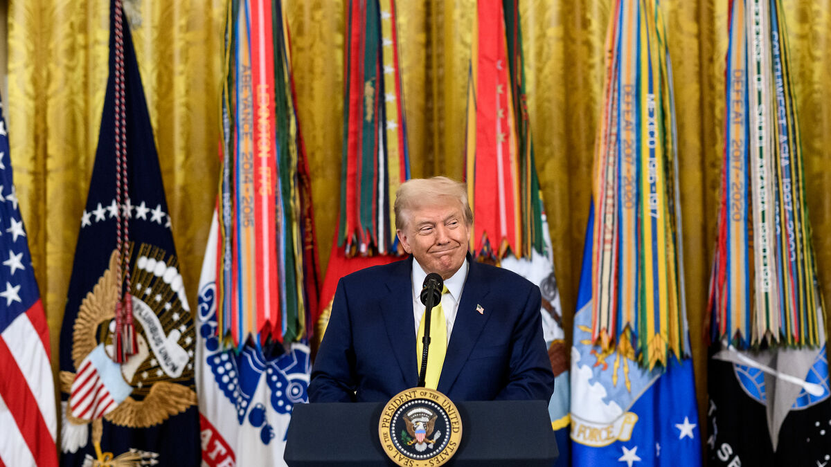 Former President Trump speaking at a podium with military flags behind him on claims about Americans preferring a dictator leader.
