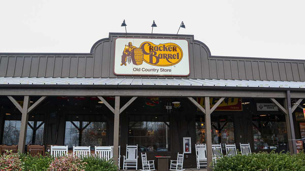 Cracker Barrel old country store exterior with classic logo on sign above rocking chairs and entrance.