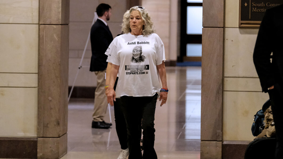 Woman wearing Ashli Babbitt t-shirt walking inside a government building related to Jan 6 Capitol rioter military funeral honors.