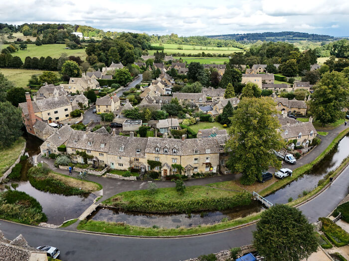 Aerial view of a village with stone houses and greenery, illustrating villagers’ fury over convoy parking at grocery store.