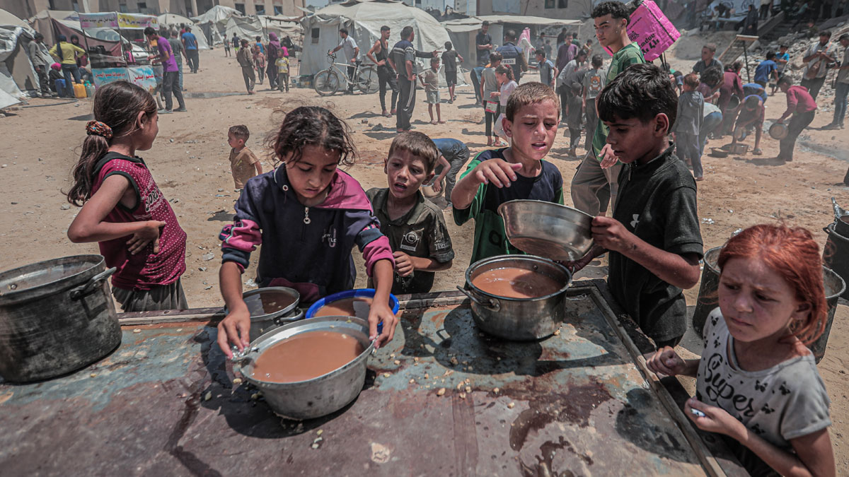 Children in Gaza receiving food at a crowded relief camp, highlighting issues with Hollywoodu2019s silence on Gaza and free press commitment.