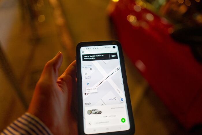 Person holding smartphone displaying ride app with map, highlighting Uber’s alleged driver screening failures.
