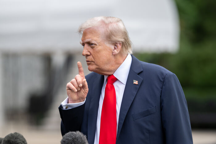 Donald Trump speaking outdoors, raising finger in a serious gesture during a media interview about ABC and Jimmy Kimmel.