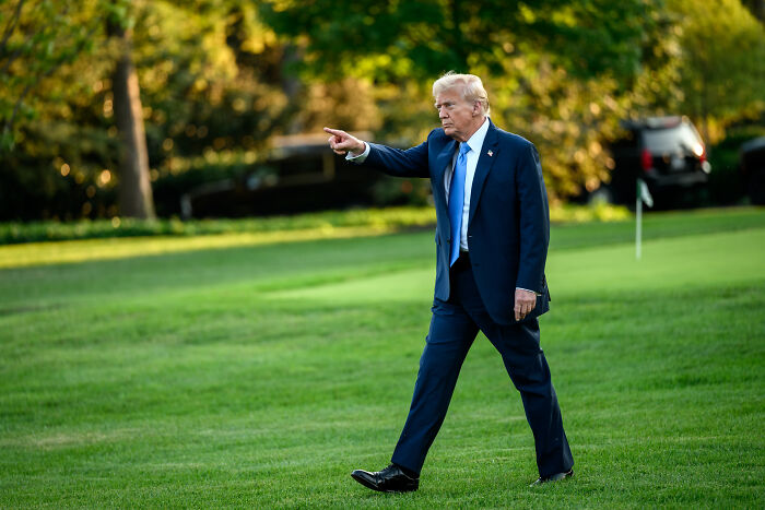 Donald Trump walking on grass outdoors, pointing forward, related to AI post and Medbed conspiracy theory controversy.