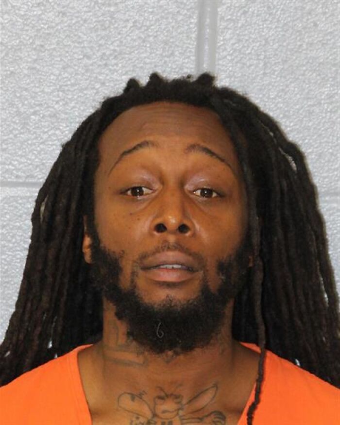 Mugshot of a man with dreadlocks and tattoos wearing an orange prison jumpsuit, related to Ukrainian refugee stabbing case. Mugshot of a man with dreadlocks and tattoos wearing an orange prison jumpsuit, related to Ukrainian refugee stabbing case.
