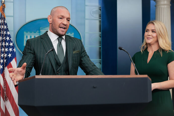 Conor McGregor speaking at a podium during a press event about his Irish presidency bid and plea for help.