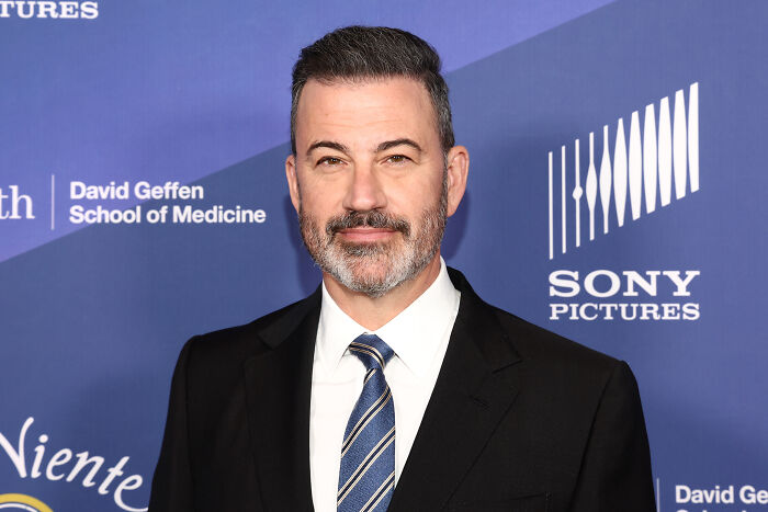 Jimmy Kimmel at a red carpet event, wearing a suit and tie, reflecting on late-night host ratings surge after suspension.
