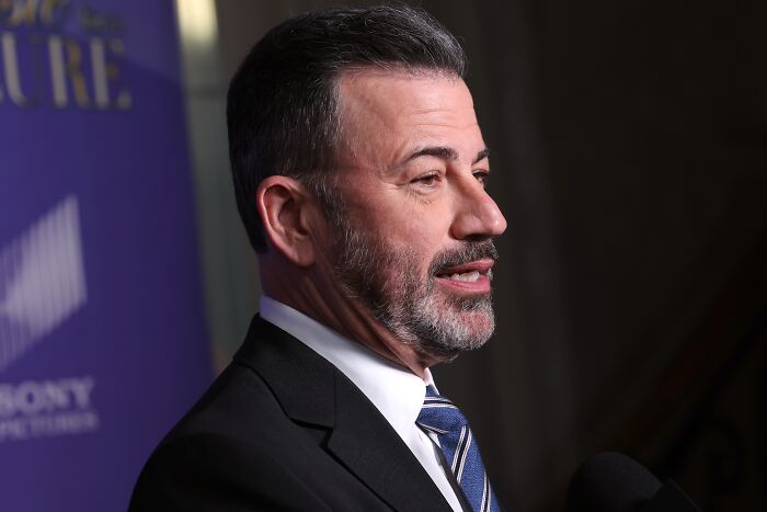 Jimmy Kimmel in a suit and striped tie speaking into a microphone during an on-air response segment. Jimmy Kimmel in a suit and striped tie speaking into a microphone during an on-air response segment.
