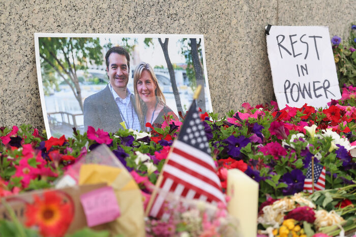 Memorial with flowers and American flags highlights concerns over America’s escalating political violence.