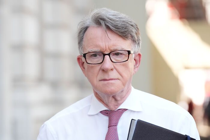 Older man in glasses and red tie holding a folder, related to U.S. ambassador fired after message to Jeffrey Epstein revealed
