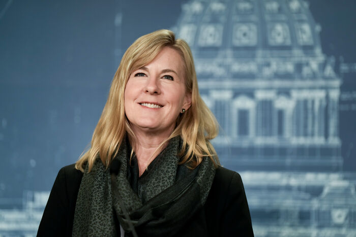 Blonde woman smiling in front of a blurred building backdrop, related to VP JD Vance transporting Charlie Kirk's casket.