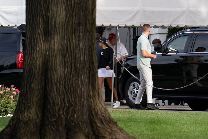 People near black SUVs outside a tent, illustrating social media impact on Donald Trump’s public presence.