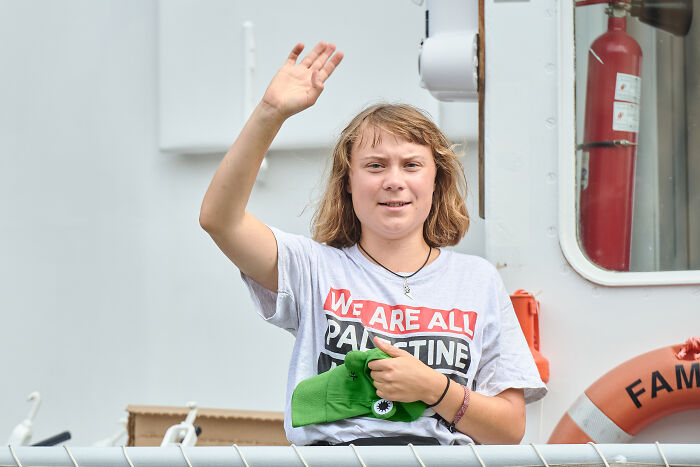 Greta Thunberg on Gaza flotilla ship, wearing a Palestine shirt and waving to the crowd during the voyage.