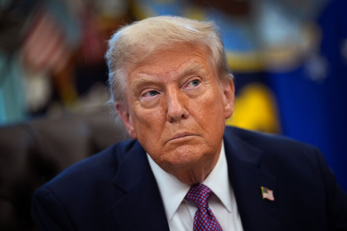 Former President Trump in a suit with an American flag pin, addressing the person in custody in connection with Charlie Kirk shooting.