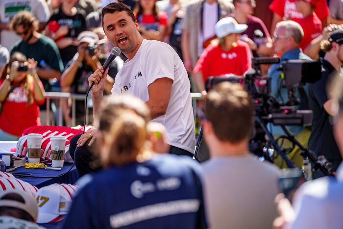 Man speaking into microphone at outdoor event with crowd, related to video of black woman shutting down Don Lemon over shooting.