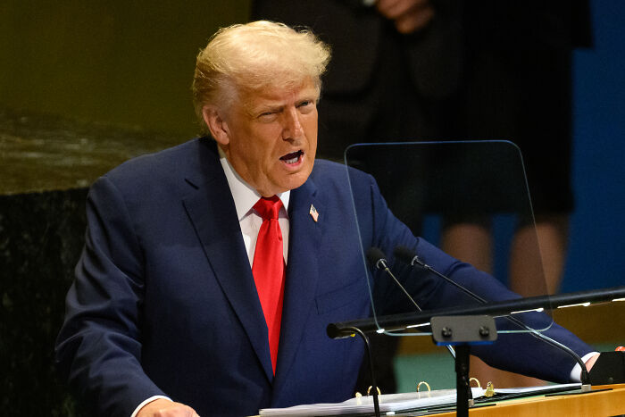 Donald Trump speaking at a podium with a microphone, White House suggesting UN staff planned to embarrass him.