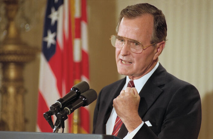 American president speaking firmly at a podium with microphones, symbolizing leadership in war efforts.