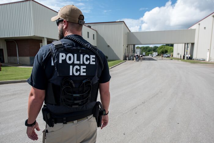 ICE police officer walking outside Texas facility amid multiple injuries and fatalities reported in shooting incident.