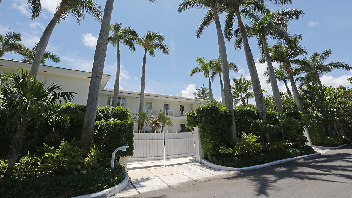 Palm Beach mansion with tall palm trees and white gate believed to be Epstein lair featured in resurfaced footage.