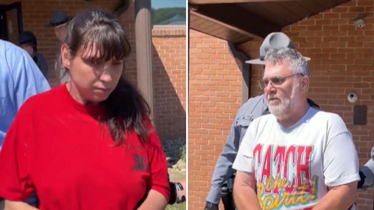 Couple arrested after 5 children found in dungeon covered in human waste and fleas, escorted by police outside brick building.
