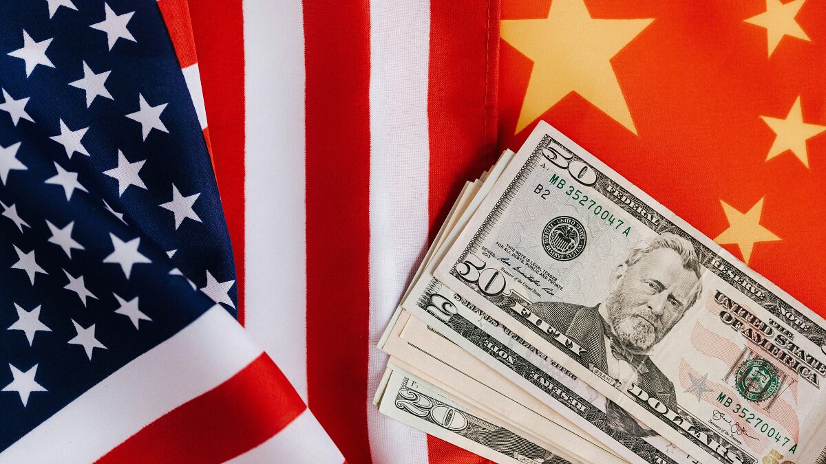 Stack of US dollar bills placed between American and Chinese flags symbolizing BRICS dollar and shifting global order.