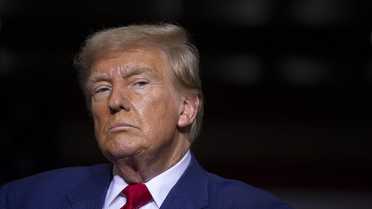 Donald Trump in a dark setting, wearing a blue suit and red tie, linked to Department of Defense rename to Department of War topic.