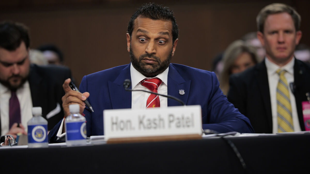Kash Patel in a blue suit reacting during a heated exchange over Epstein files in a formal congressional hearing setting.