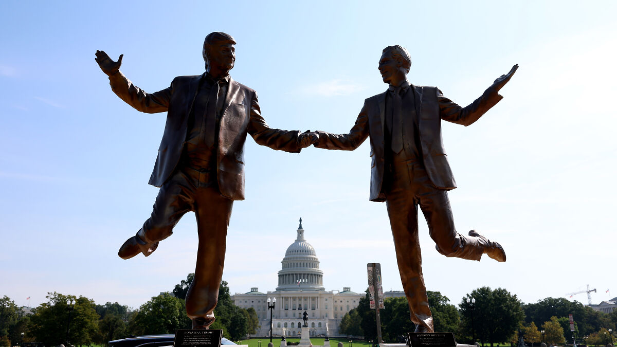 Bronze Trump and Epstein statue holding hands with one leg raised, displayed outdoors near U.S. Capitol in Washington D.C.