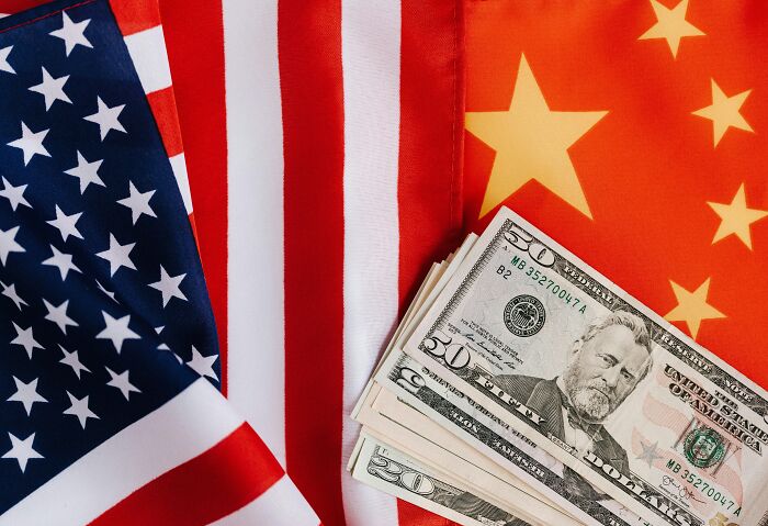 Close-up of US dollar bills on the American and Chinese flags representing Brics dollar impact on global order.
