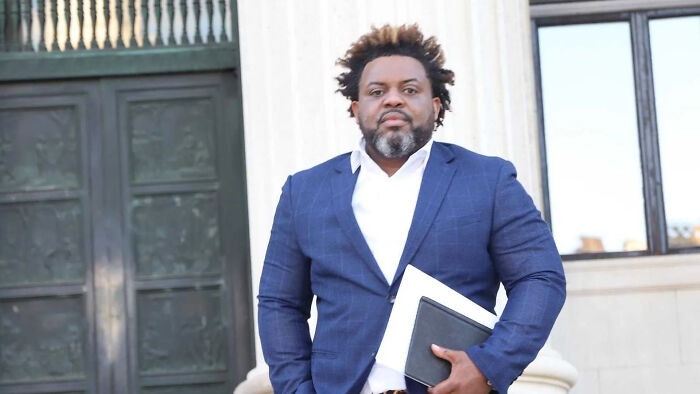 Man in a blue suit standing outside a government building, holding documents related to aide arrest for c*****e shipment. Man in a blue suit standing outside a government building, holding documents related to aide arrest for c*****e shipment.