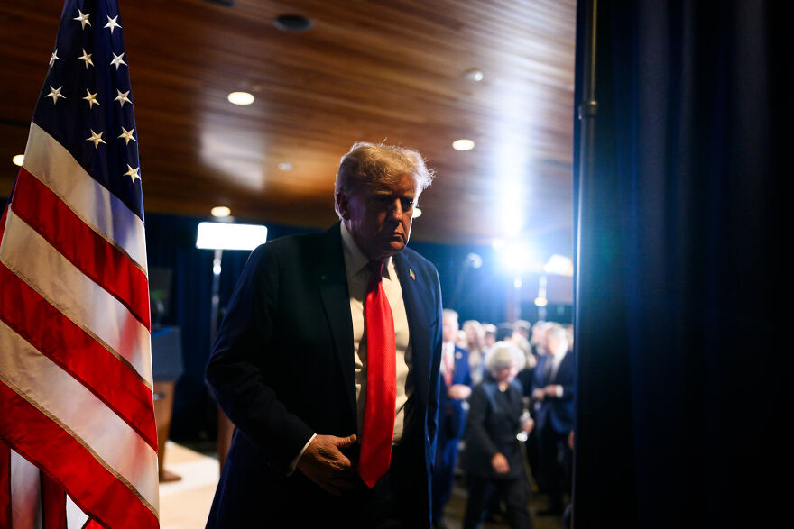 Former President Trump in a dimly lit room with the American flag, connected to White House shared doctored photo SEO keywords.