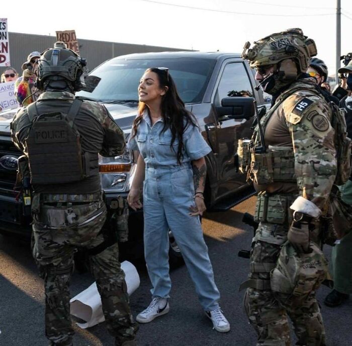Protester confronts National Guard troops in tactical gear during Chicago deployment dispute amid public demonstration. Protester confronts National Guard troops in tactical gear during Chicago deployment dispute amid public demonstration.