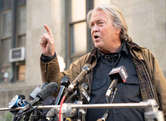Steve Bannon speaking at a press conference, sharing a sinister clip suggesting Trump’s presidency will continue indefinitely.