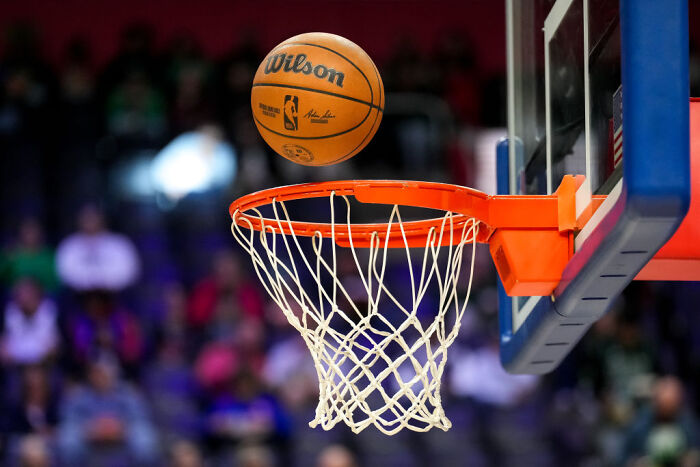 NBA basketball close to hoop during a game, representing FBI gambling cases involving rigged games and insider bets. NBA basketball close to hoop during a game, representing FBI gambling cases involving rigged games and insider bets.
