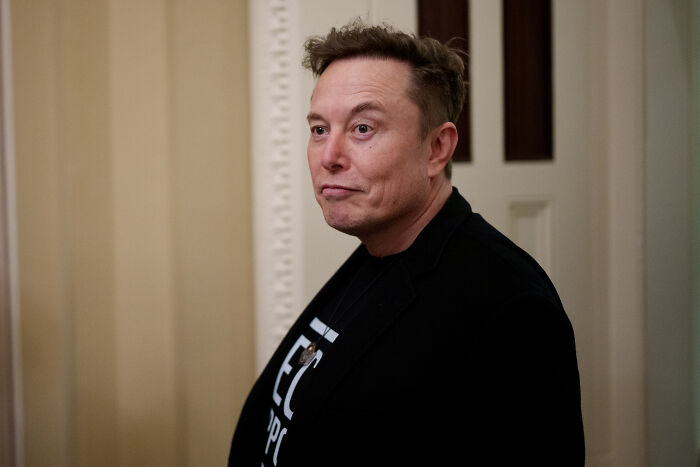Elon Musk in a black jacket indoors, related to Musk joining Netflix boycott over pro-trans cartoon controversy.