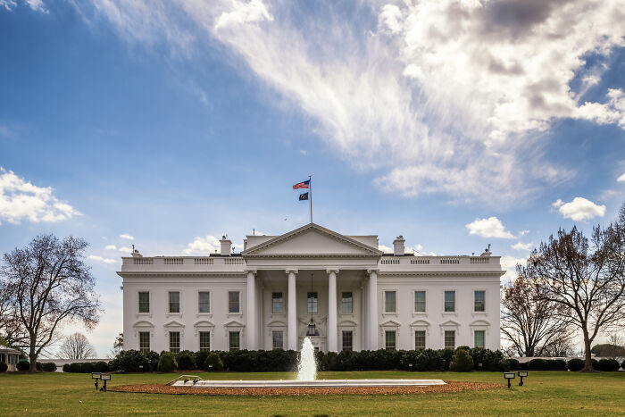 The White House with a fountain in front under a partly cloudy sky related to Trump supporter visa threat news. The White House with a fountain in front under a partly cloudy sky related to Trump supporter visa threat news.