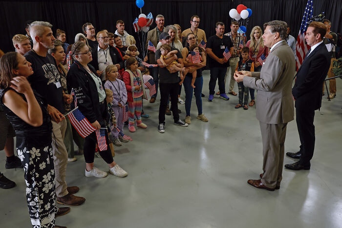Group of people holding American flags listening to a speaker discussing U.S. refugee cap and White South Africans. Group of people holding American flags listening to a speaker discussing U.S. refugee cap and White South Africans.