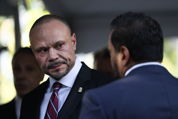 A serious man in a suit and striped tie talks with another man, related to Biden’s FBI monitored Republican senators.