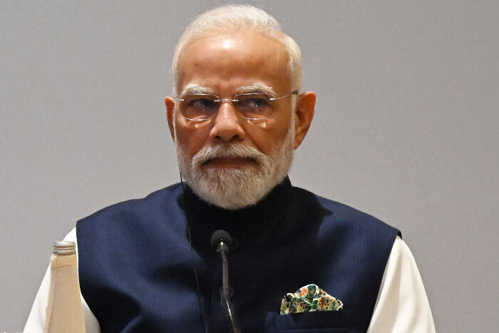 Prime Minister Narendra Modi seated wearing glasses and a navy vest at Asia Summit event with serious expression. Prime Minister Narendra Modi seated wearing glasses and a navy vest at Asia Summit event with serious expression.