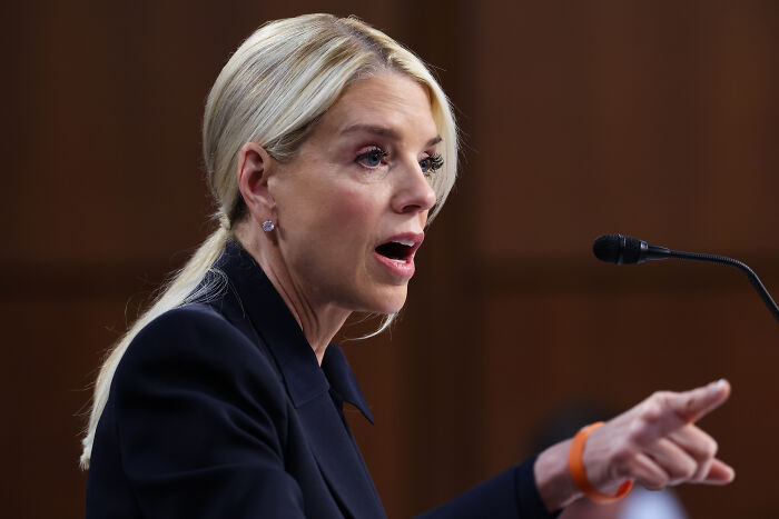 Woman with blonde hair speaking passionately at a microphone, Bondi dodges questions about Trump photos linked to Epstein investigation.
