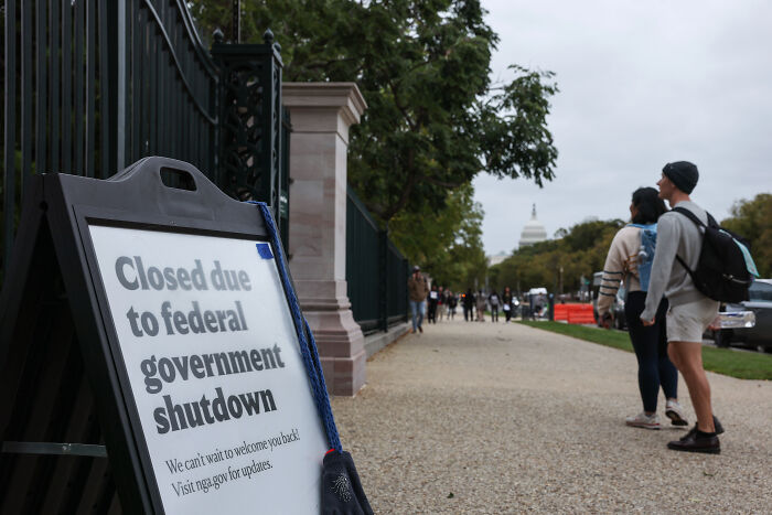 Sign about federal government shutdown outside Capitol, with pedestrians walking nearby, relating to Bernie Sanders and Trump trolling campaign. Sign about federal government shutdown outside Capitol, with pedestrians walking nearby, relating to Bernie Sanders and Trump trolling campaign.