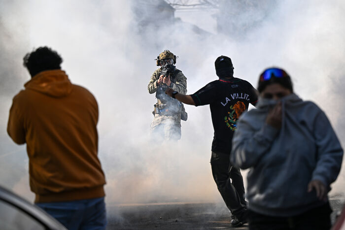 Protester faces armed officer in smoke-filled street during tense scene linked to ICE raids in Chicago. Protester faces armed officer in smoke-filled street during tense scene linked to ICE raids in Chicago.