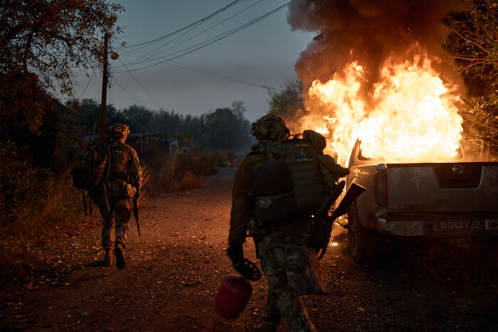 Two soldiers walk near a burning vehicle as Russian leader flexes his nukes amid rising tensions. Two soldiers walk near a burning vehicle as Russian leader flexes his nukes amid rising tensions.