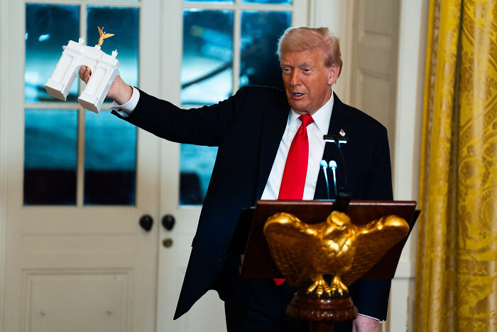 Donald Trump holding a white decorative model in the White House, highlighting design disasters in costly renovation project. Donald Trump holding a white decorative model in the White House, highlighting design disasters in costly renovation project.