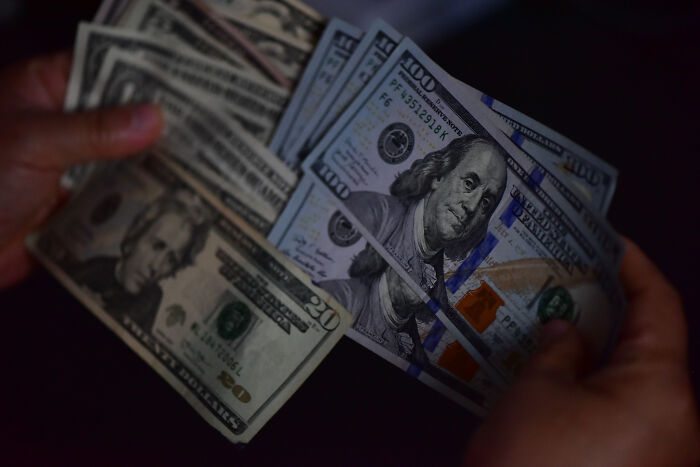 Hands holding US dollar bills representing FBI NBA gambling cases involving mafia money and insider bets. Hands holding US dollar bills representing FBI NBA gambling cases involving mafia money and insider bets.