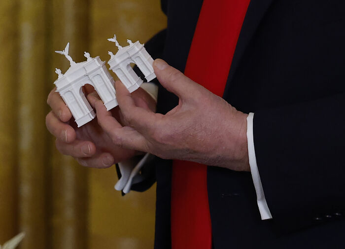Close-up of hands holding small white architectural models representing D.C. renovations tied to Trump’s controversial oversight changes. Close-up of hands holding small white architectural models representing D.C. renovations tied to Trump’s controversial oversight changes.
