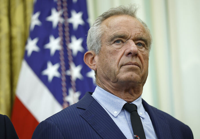 Man in a navy suit and tie standing in front of an American flag, symbolizing government focus during shutdown Man in a navy suit and tie standing in front of an American flag, symbolizing government focus during shutdown