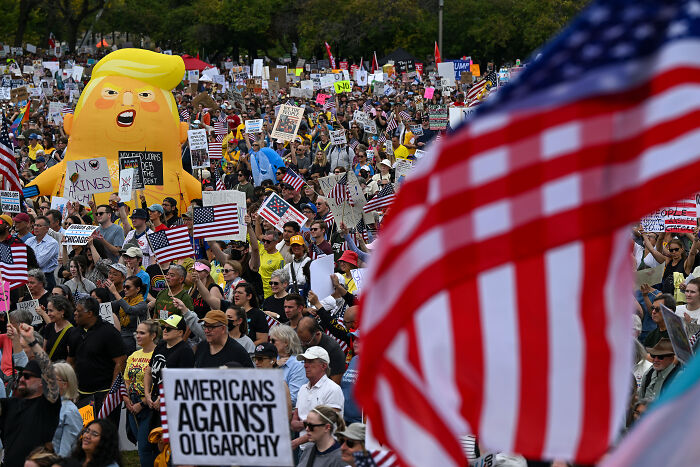 Crowd at a protest with American flags and signs showing Americans against oligarchy during government shutdown focus. Crowd at a protest with American flags and signs showing Americans against oligarchy during government shutdown focus.